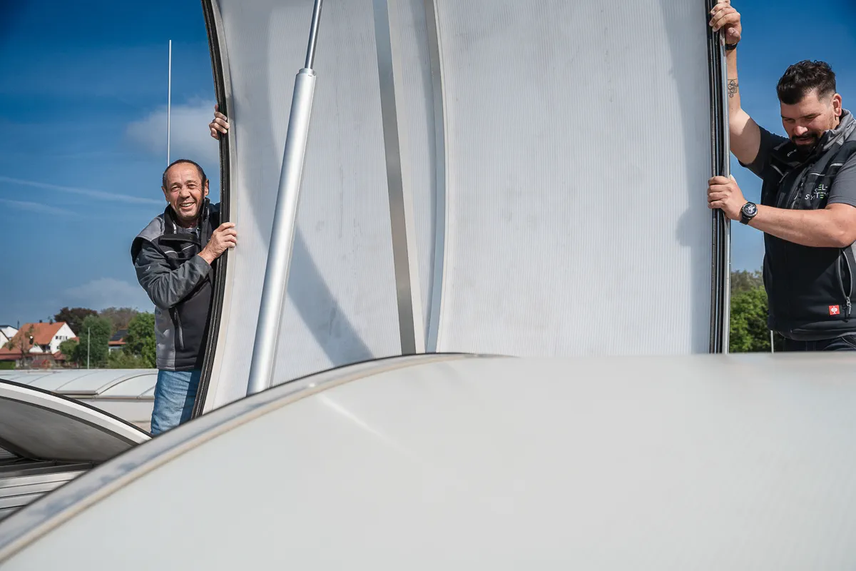 Zwei Mitarbeiter von SCEL-SYSTEMS bei der gemeinsamen Wartung einer Lichtkuppel im Bereich technischer Brandschutz